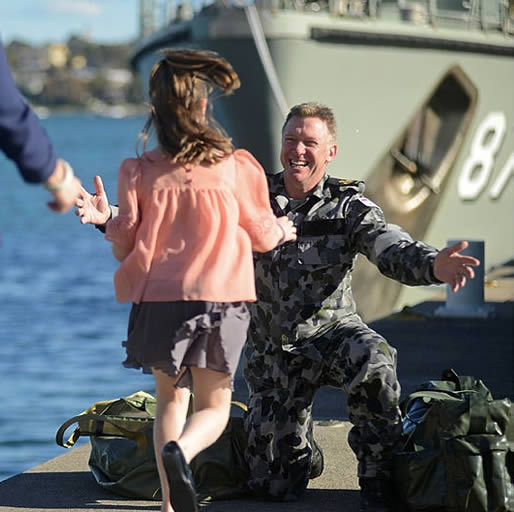 Girl running to her father who has just returned from a navy deployment.