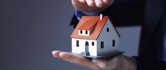 Person holding model house in their hands.