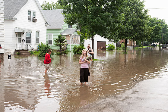 Family standing in floodwaters outside their flooded home.