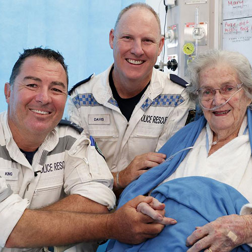 An elderly woman assisted by two male nurses.