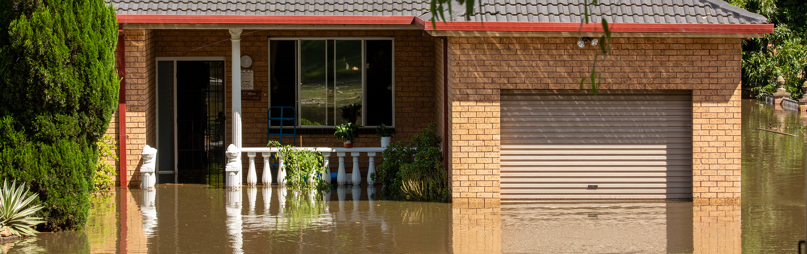 A flooded house showing the front of a brick home partially under water.